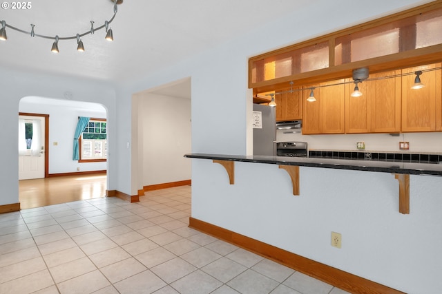 1710 Norkenzie Rd, Eugene, OR 97401 - kitchen with a kitchen bar, stove, extractor fan, dark countertops, and light tile patterned floors