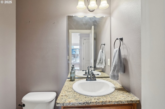 229 N 33rd Ct, Ridgefield, WA 98642 - bathroom with toilet, vanity, a textured wall, and a chandelier