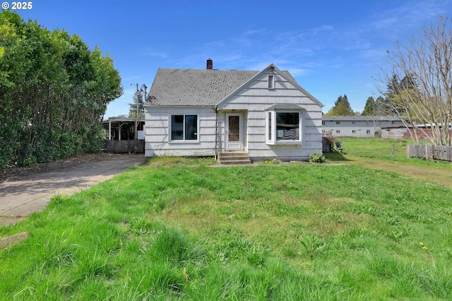 bungalow featuring a front yard and a chimney