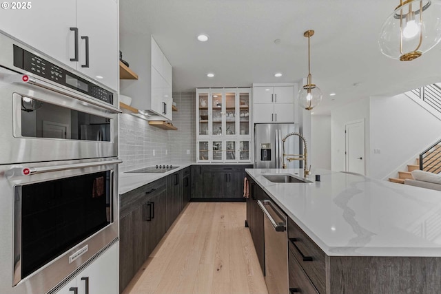 kitchen with light wood finished floors, a sink, white cabinets, appliances with stainless steel finishes, and modern cabinets