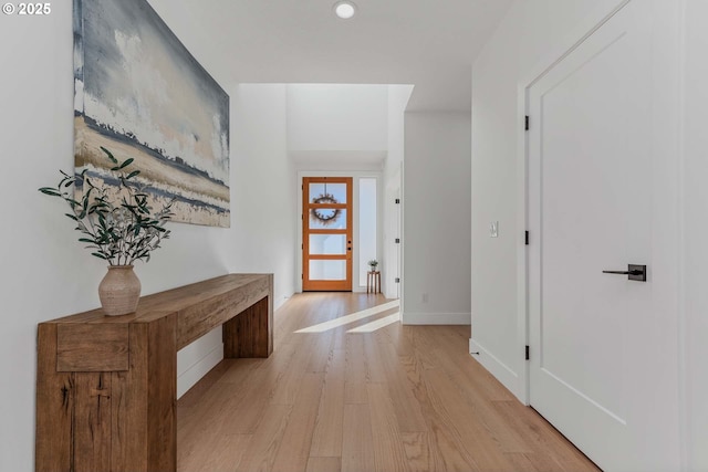 corridor with baseboards and light wood finished floors