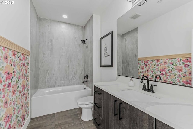 bathroom with visible vents, toilet, vanity, and shower / tub combination