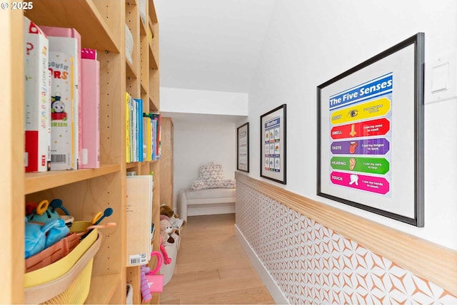 corridor featuring wood finished floors and wainscoting