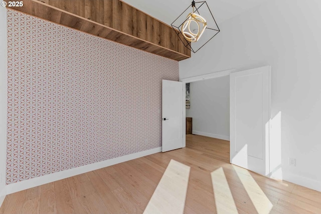 interior space with wallpapered walls, wood finished floors, and baseboards