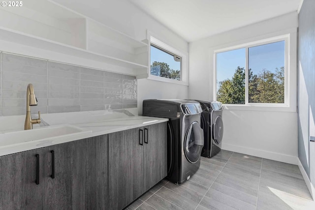 clothes washing area featuring separate washer and dryer, baseboards, a wealth of natural light, and a sink