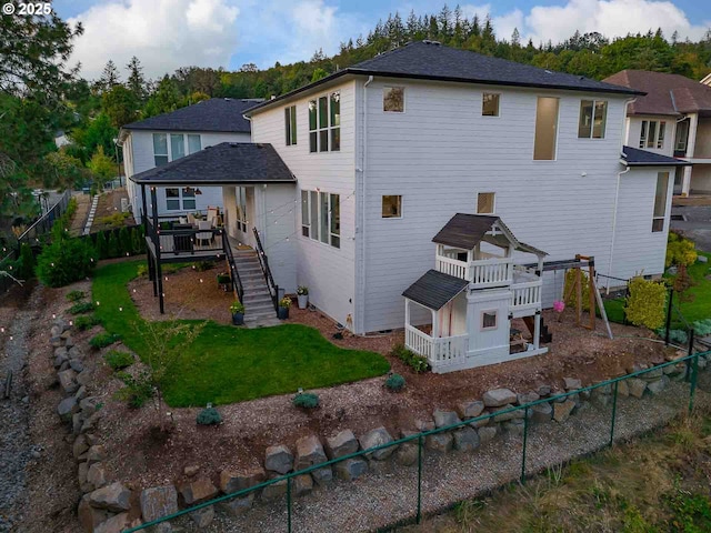 rear view of property with a deck, stairway, a yard, and a fenced backyard