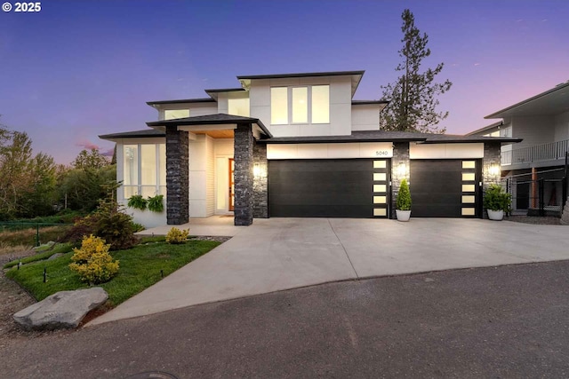 view of front of house with stone siding, driveway, and stucco siding