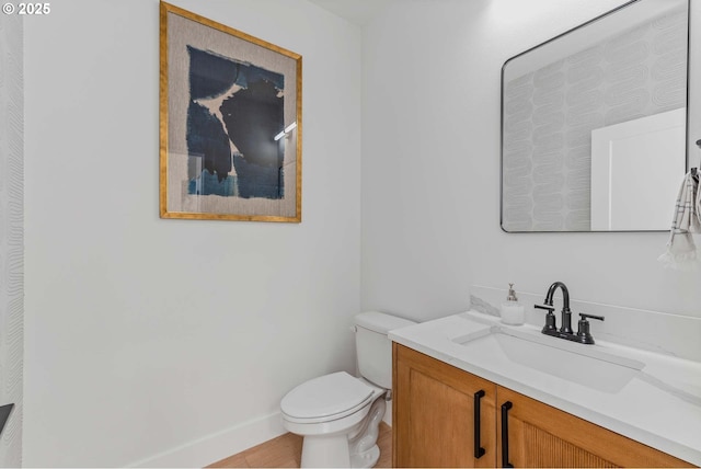 bathroom with baseboards, toilet, and vanity