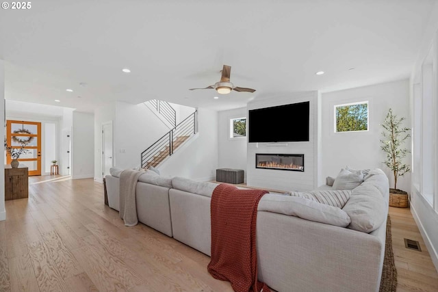 living area with light wood finished floors, visible vents, stairway, recessed lighting, and a fireplace