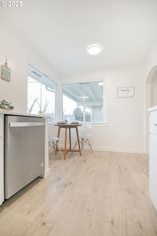 interior space featuring arched walkways, light wood-type flooring, and baseboards