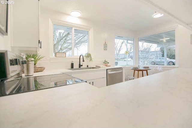 kitchen with decorative backsplash, dishwasher, white cabinets, light countertops, and a sink