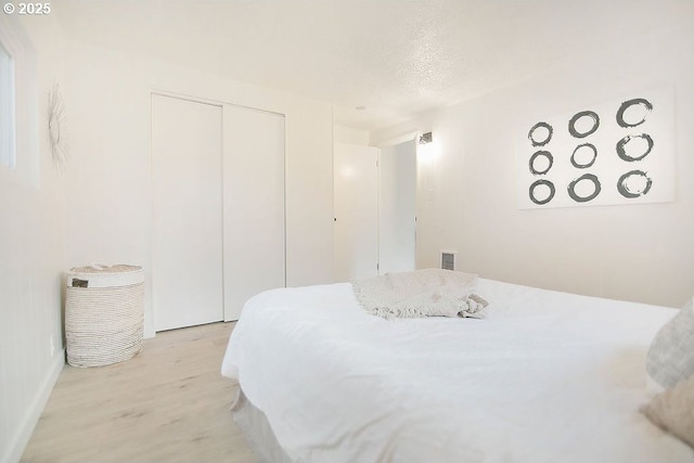 bedroom with a closet, visible vents, and light wood-style flooring