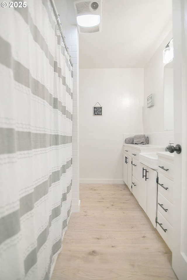 bathroom with baseboards, wood finished floors, and vanity