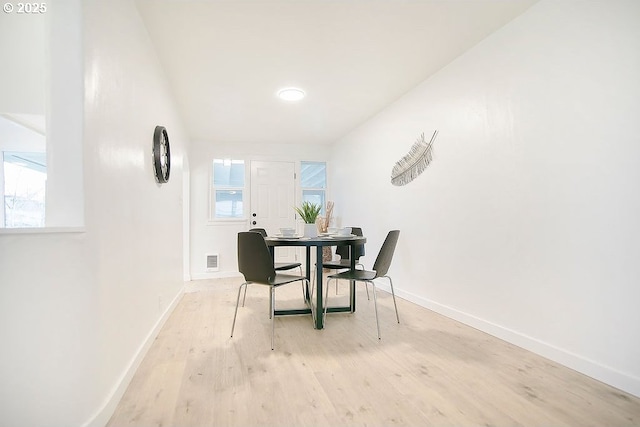 dining area with light wood-type flooring, visible vents, and baseboards