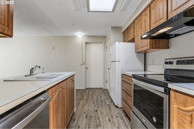 6095 SW Erickson Ave, Beaverton, OR 97008 - kitchen featuring stainless steel appliances, under cabinet range hood, a sink, brown cabinetry, and light wood-style floors