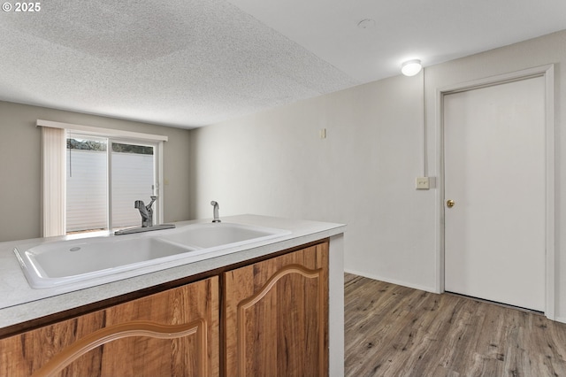 6095 SW Erickson Ave, Beaverton, OR 97008 - kitchen featuring brown cabinets, light wood finished floors, a sink, light countertops, and a textured ceiling