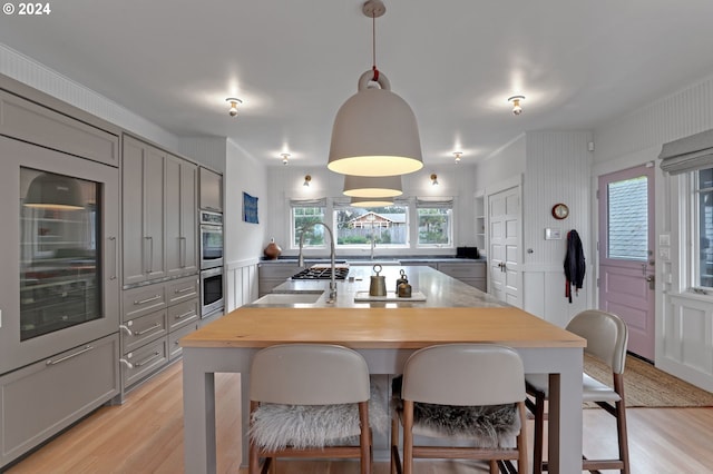 486 N Ocean Ave, Gearhart, OR 97138 - kitchen with a decorative wall, gray cabinets, light wood-type flooring, and a center island with sink
