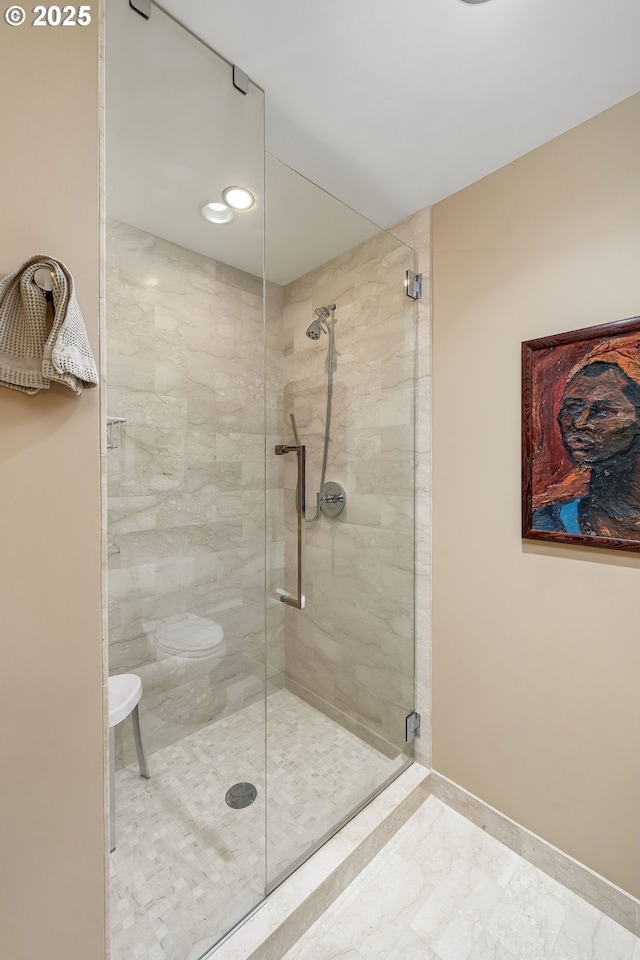 full bath featuring a shower stall, baseboards, and toilet