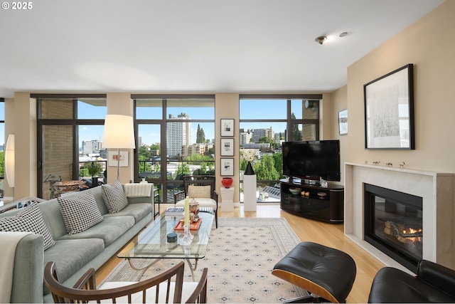 living area featuring light wood-type flooring, a high end fireplace, and a wall of windows