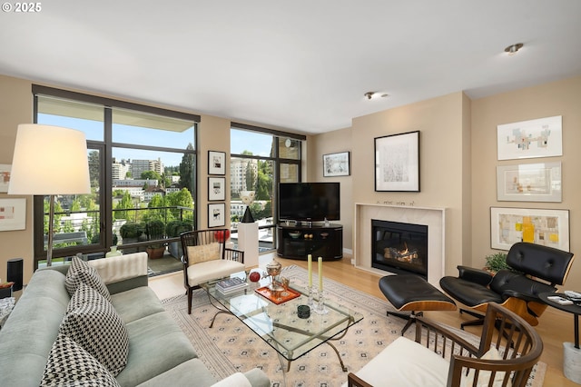 living area with wood finished floors, floor to ceiling windows, and a high end fireplace