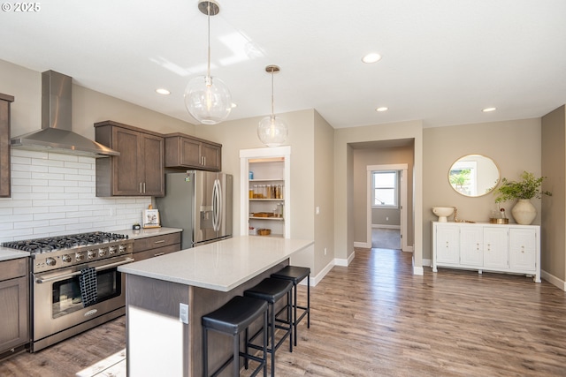 840 Chikamin Loop, Silverton, OR 97381 - kitchen with appliances with stainless steel finishes, wall chimney range hood, a breakfast bar area, tasteful backsplash, and baseboards