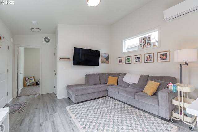 living room featuring visible vents, baseboards, a wall unit AC, and wood finished floors