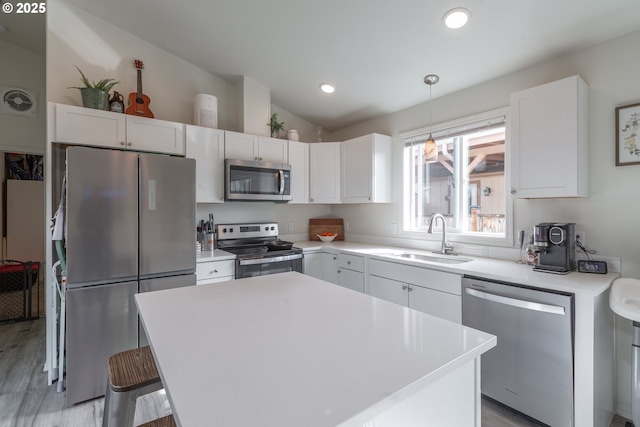 kitchen with light countertops, vaulted ceiling, white cabinets, stainless steel appliances, and a sink