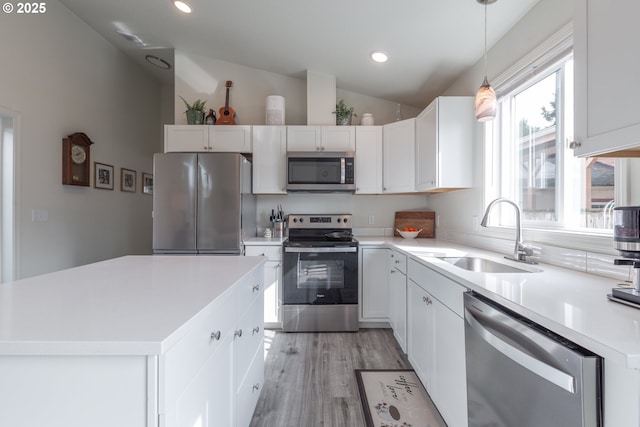 kitchen with appliances with stainless steel finishes, white cabinetry, lofted ceiling, and a sink