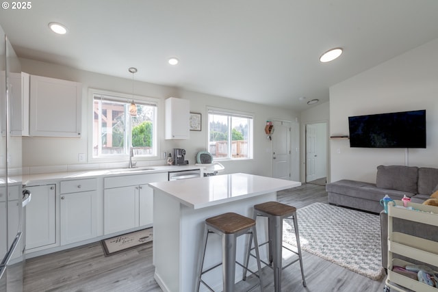 kitchen featuring a breakfast bar, a sink, a center island, white cabinets, and lofted ceiling