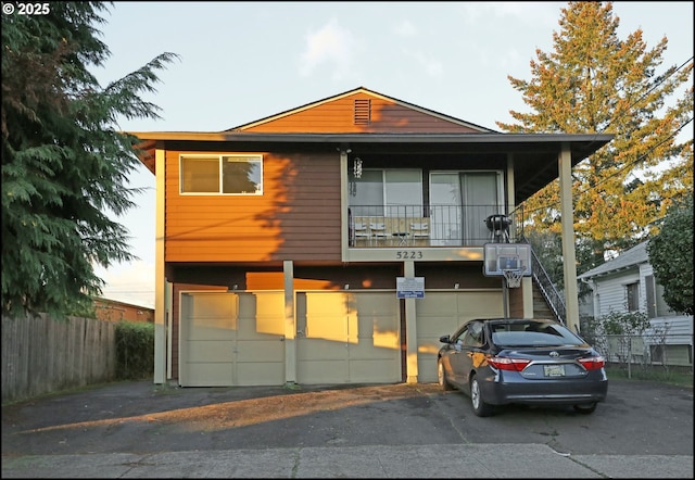 view of front of property with aphalt driveway, an attached garage, and fence