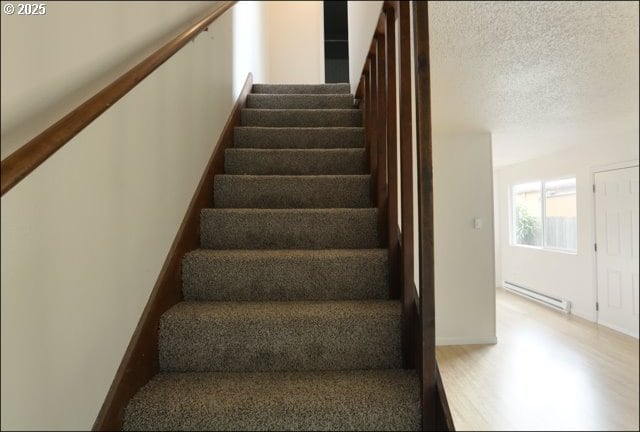 stairs featuring a textured ceiling, baseboard heating, and baseboards