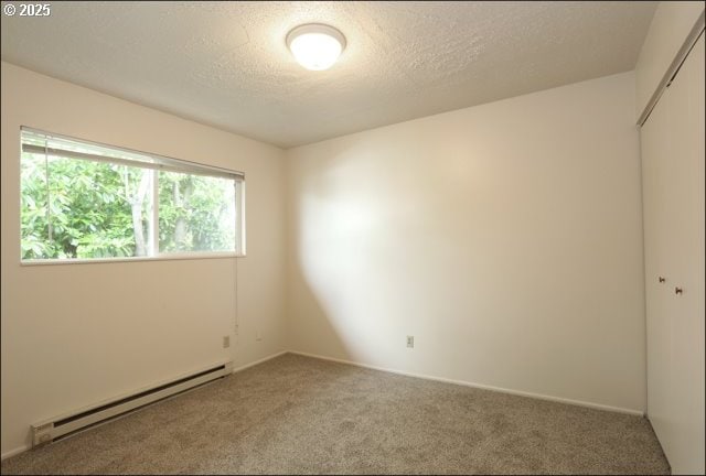 unfurnished room featuring a baseboard heating unit, a textured ceiling, and carpet