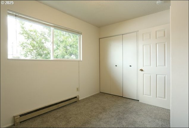 unfurnished bedroom featuring carpet, baseboard heating, and a closet