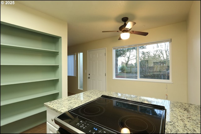 kitchen featuring ceiling fan, built in shelves, range with electric stovetop, white cabinets, and light stone countertops