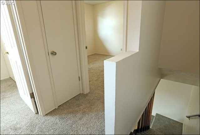 hallway featuring light colored carpet and an upstairs landing