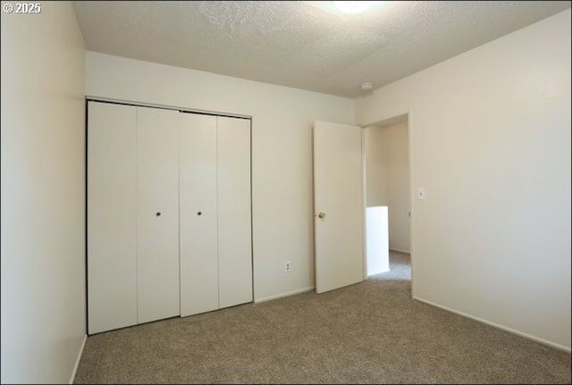 unfurnished bedroom with a textured ceiling, carpet floors, and a closet