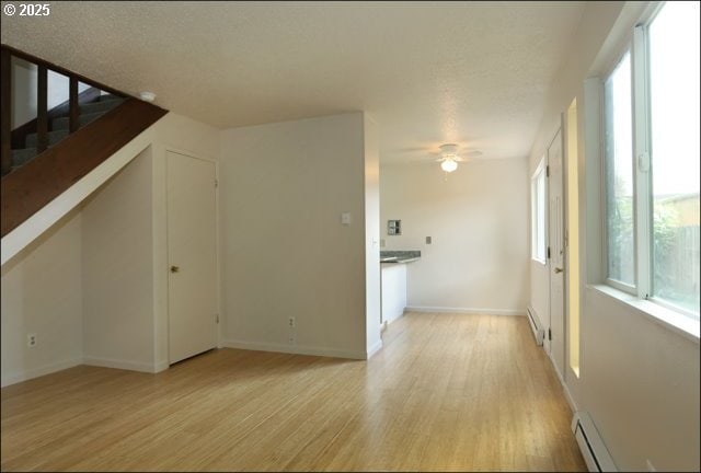 interior space with baseboards, ceiling fan, light wood-style flooring, and baseboard heating