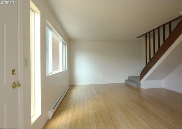 interior space with light wood-type flooring, stairs, and a baseboard heating unit