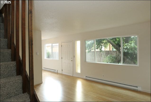 foyer featuring a baseboard heating unit, wood finished floors, and stairs