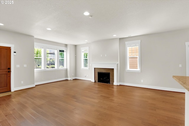 385 SW Mitchum Ter, Beaverton, OR 97006 - unfurnished living room featuring wood finished floors, a tiled fireplace, recessed lighting, and a textured ceiling