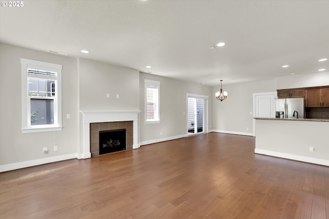 385 SW Mitchum Ter, Beaverton, OR 97006 - unfurnished living room with a chandelier, a fireplace, dark wood finished floors, and recessed lighting