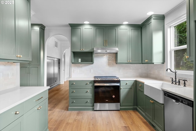 2089 5th Ave, West Linn, OR 97068 - kitchen featuring green cabinets, appliances with stainless steel finishes, under cabinet range hood, arched walkways, and crown molding
