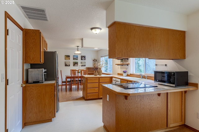4216 SW Brugger St, Portland, OR 97219 - kitchen with black appliances, a peninsula, tile counters, brown cabinetry, and a textured ceiling
