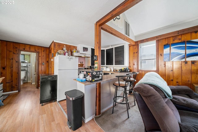 kitchen featuring wood walls, freestanding refrigerator, light wood finished floors, open floor plan, and black dishwasher