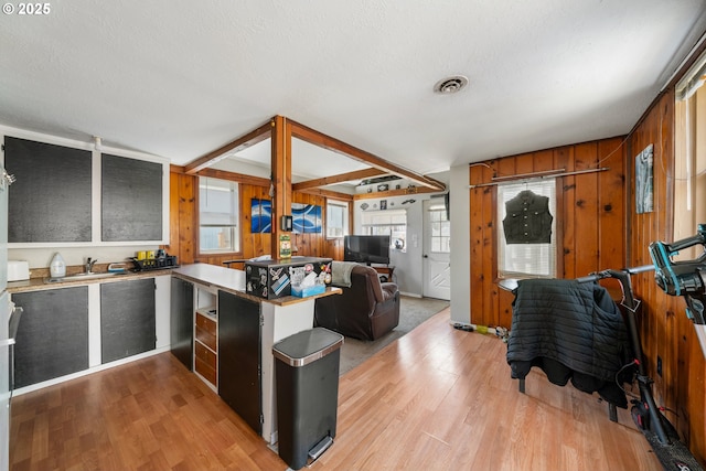 kitchen with a peninsula, open floor plan, visible vents, and light wood finished floors