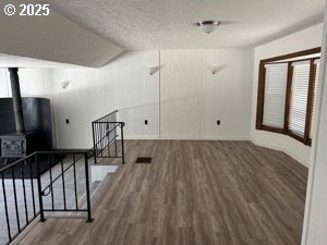 unfurnished living room featuring vaulted ceiling, dark hardwood / wood-style flooring, and a textured ceiling