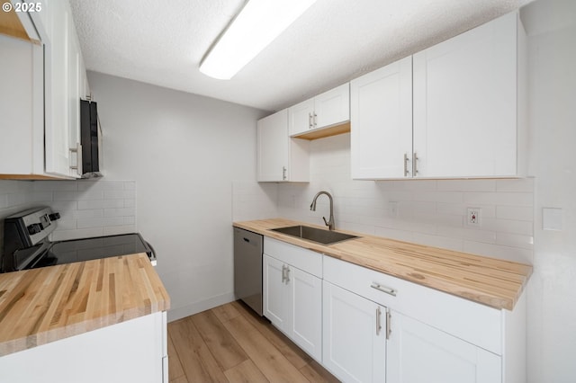 kitchen with butcher block counters, white cabinetry, sink, stainless steel dishwasher, and range