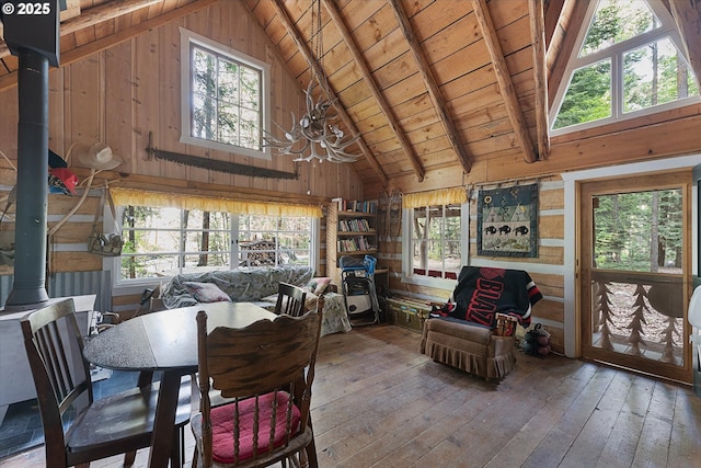 dining space featuring a wood stove, wooden ceiling, wooden walls, high vaulted ceiling, and a chandelier