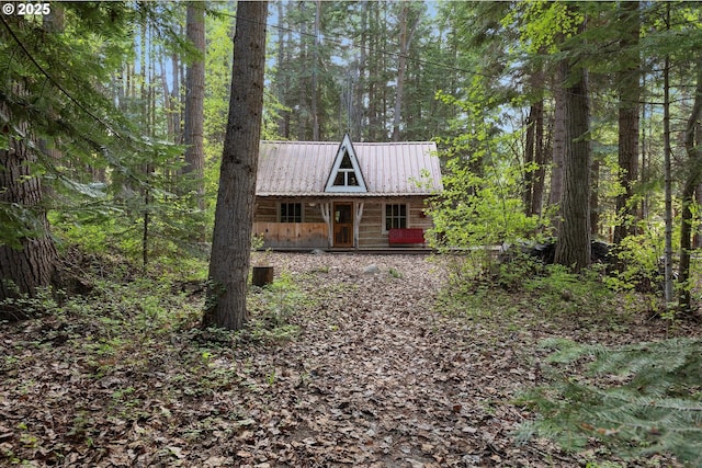 view of front of home with metal roof, a forest view, and covered porch