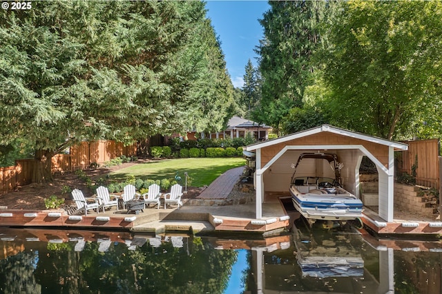 view of dock featuring a water view, an outdoor fire pit, fence, and a lawn